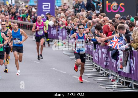 Song-ming Syu club runner running in the TCS London Marathon 2022 road race in Tower Hill, City of London, UK. Interacting with large crowd, support Stock Photo