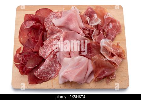 Cold cuts on wooden cutting board, slices of bresaola, salami, ham and Parma ham, isolated on white Stock Photo