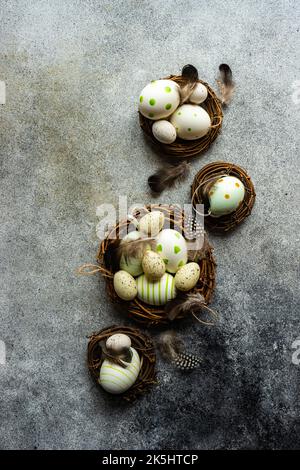 Overhead view of four bird's nests filled with painted easter eggs and feathers Stock Photo