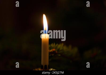 Dim light from a single candle in the dark, Christmas lighting, symbolic image save electricity, power failure, blackout Stock Photo