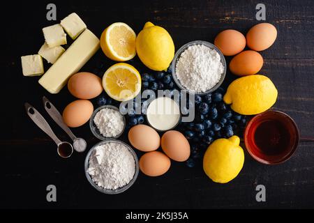 Blueberry–Lemon Curd Tart Raw Ingredients on a Wood Table: Fresh blueberries, lemons, and other uncooked ingredients on a dark background Stock Photo