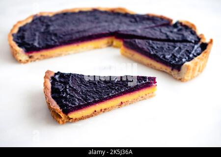 Sliced Blueberry–Lemon Curd Tart Viewed from Above: Layered blueberry-lemon tart on a white marble background Stock Photo