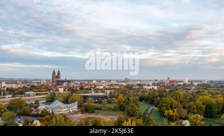 Autumnal deciduous trees in the Rotehorn municipal park, behind them listed hypar shell, Magdeburg Cathedral, Our Lady's Convent, St. John's Church Stock Photo