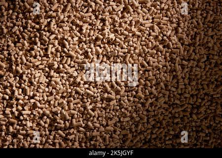Top view of pile of compressed cylinder shaped wood fuel pellets scattered on table as textured background Stock Photo