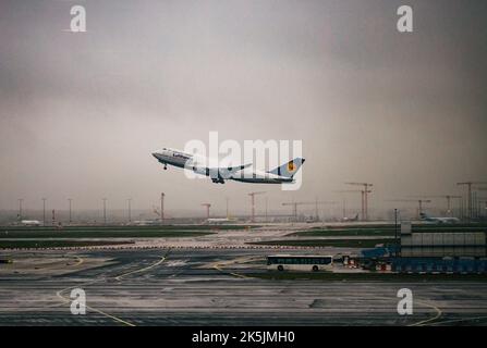 A Lufthansa plane taking off from the Frankfurt airport under a gloomy sky on a rainy day in Germany Stock Photo