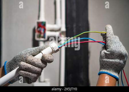 Electrician pulling wire into PVC Conduit Stock Photo