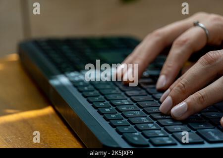 young mexican latina woman, typing on a wireless keyboard on her computer Stock Photo