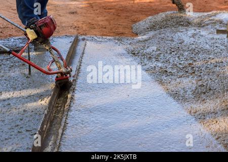 New driveway construction involves the use machine to align fresh concrete compacted layer level Stock Photo