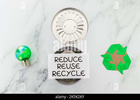 reduce reuse recycle sign with mini trash can next to green light bulb ...