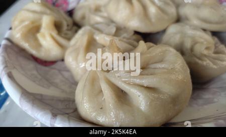 tibetan momo dumplings served steaming hot on a plate with stuffings of pork, chicken, cabbage etc. A popular delicacy in winter season. Stock Photo
