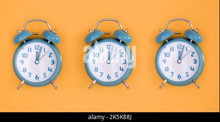 Blue alarm clocks on orange background isolated, flat lay. Stock Photo
