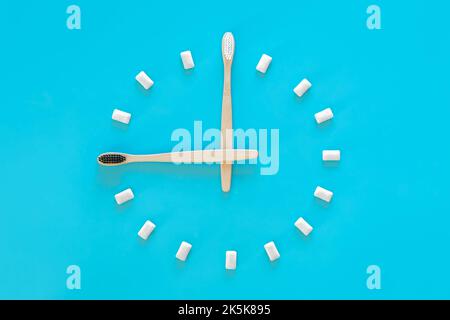 Flat lay, a clock made of chewing gum on a blue background and a toothbrush. Stock Photo