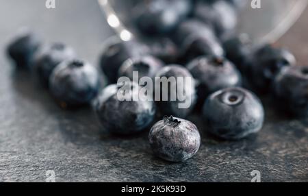 Macro photography, blueberries scattered on a dark surface. Stock Photo