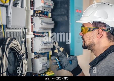 Man, an electrical technician working in a switchboard with fuses. Stock Photo