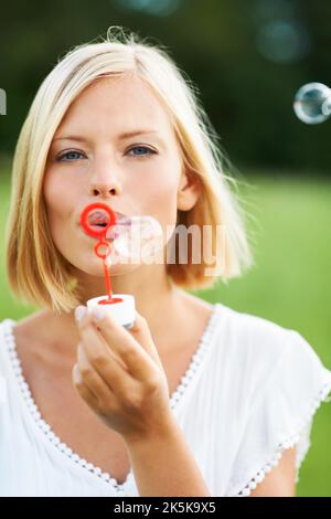 Look at all the bubbles. Cute young woman blowing soap bubbles outdoors. Stock Photo