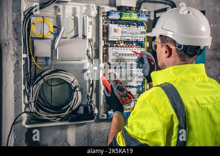Man, an electrical technician working in a switchboard with fuses. Stock Photo