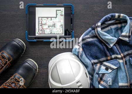 Digital tablet with layout and worker clothes, top view. Stock Photo