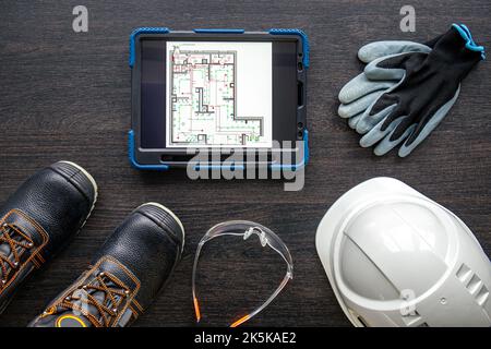 Digital tablet with layout and worker clothes, top view. Stock Photo