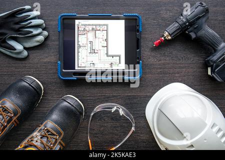 Digital tablet with layout and worker clothes, top view. Stock Photo