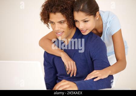 Looking at our options together. Gorgeous young couple looking at a laptop together. Stock Photo