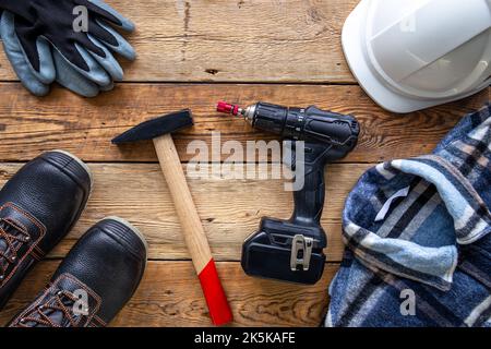 Uniform and construction tools on wooden table, top view. Stock Photo