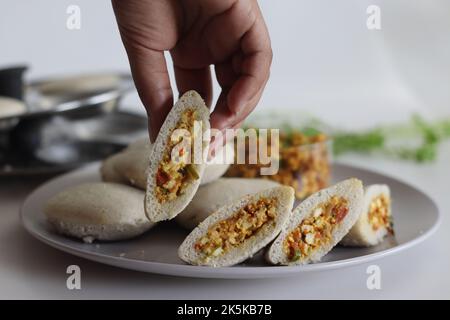 Paneer stuffed kodo millet Idly. Steamed savory cakes made of kodo millets and lentil flour stuffed with a patty made of scrambled cottage cheese with Stock Photo