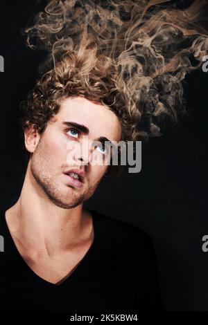 Going up in smoke. An intoxicated man looking up as his hair smokes. Stock Photo