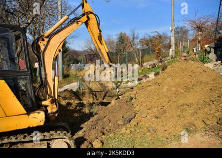 A road excavator dredges the hole near the family house Stock Photo