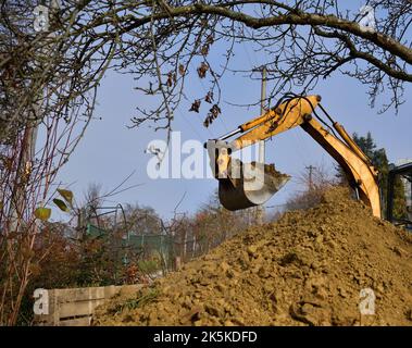 A road excavator dredges the hole near the family house Stock Photo