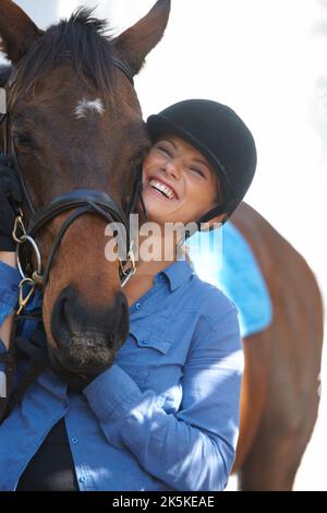 She loves her horse. A young woman smiling happily while outside with her horse. Stock Photo