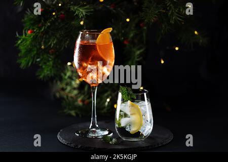 Cocktail called orange spritz and gin tonic or Moscow mule in dark party mood. Celebration scene with dark background. Christmas or New Year Party dec Stock Photo