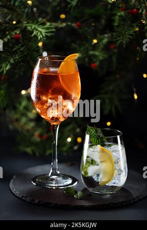 Cocktail called orange spritz and gin tonic or Moscow mule in dark party mood. Celebration scene with dark background. Christmas or New Year Party dec Stock Photo