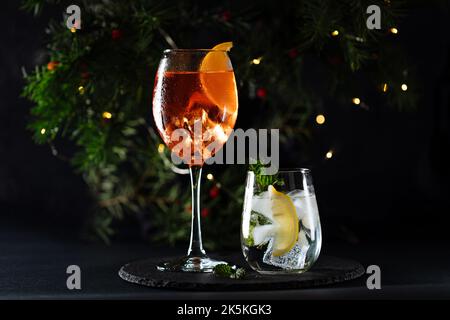 Cocktail called orange spritz and gin tonic or Moscow mule in dark party mood. Celebration scene with dark background. Christmas or New Year Party dec Stock Photo