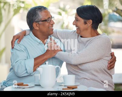 Senior couple laughing, drinking coffee and bonding in backyard cafe together, relax and cheerful outdoors. Elderly man and woman enjoying retirement Stock Photo