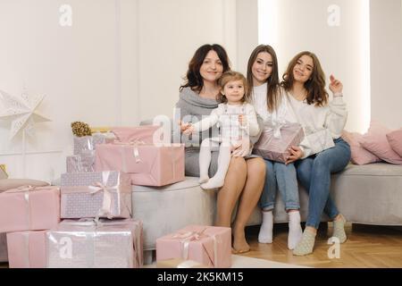 Four woman of different ages at Christmas time. From granddaughter to grandmother. Presents on the floor Stock Photo