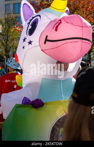 A man wearing a unicorn costume is having fun in the crowd during Birmingham Pride. Stock Photo