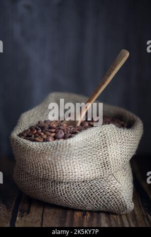 Coffee beans in jute bag-sack and wooden spoon on table Stock Photo