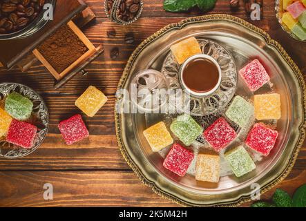 Turkish coffee cup placed with roasted coffee beans and Turkish delights on rustic wooden background. Top view with copy space. Stock Photo