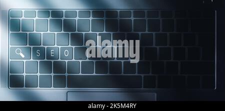 Laptop keyboard with blue light and SEO text on buttons. SEO Search Engine Optimization concept. Ranking traffic on website. Stock Photo