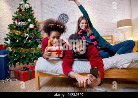 Group young friends taking selfie with excited and enjoy with smart phone together at home, man and woman taking a photo in celebration xmas eve with Stock Photo