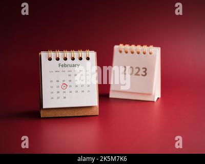 Happy Valentine's day, February 2023 calendar desk on red background. Red circle draws hand mark on day 14 on white table calendar with the February m Stock Photo
