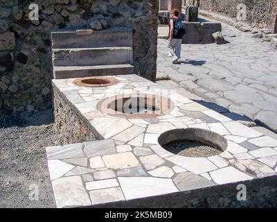 Counter in a shop with holes for barrels of grain in Pompeii, Italy Stock Photo