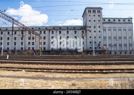 Railroad tracks and a train against the backdrop of an abandoned and destroyed industrial building. Stock Photo