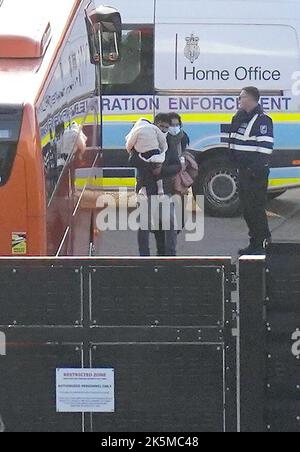 A man carries a young child as a group of people thought to be migrants walk through the Border Force compound in Dover, Kent, after being brought from a Border Force vessel following a small boat incident in the Channel. Picture date: Sunday October 9, 2022. Stock Photo