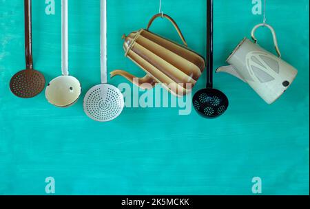 Vintage enamel kitchen utensils and coffee pots,food and drink, nostalgic items,hanging on teal background,free copy space Stock Photo