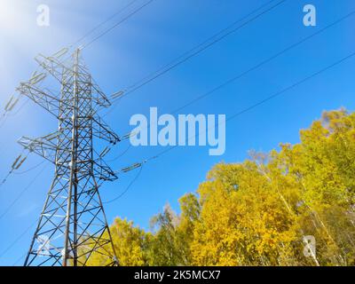 Power lines and a tower against a background of blue sky an sun in autumn time Stock Photo
