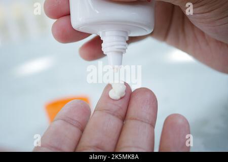 Close up of person hand using sunscreen cream  Stock Photo