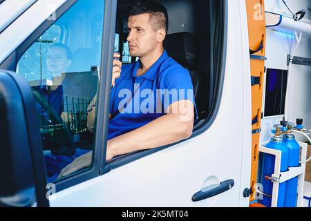 Team of paramedics preparing to leave for emergency ambulance call while sitting inside vehicle. Emergency medical services Stock Photo