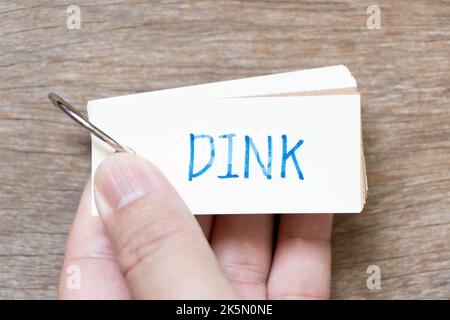 Hand hold flash card with handwriting in word DINK (Abbreviation of Double income, no kids or Dual income, no kids) on wood background Stock Photo