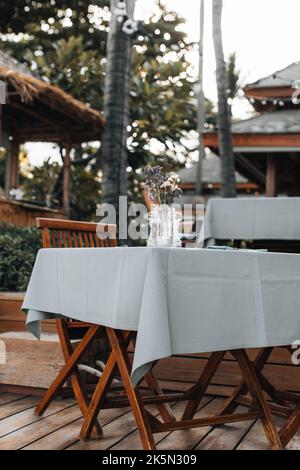 Tableclothed table and wooden chairs in a summer outdoor restaurant Stock Photo